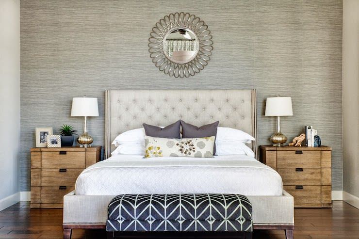 طراحی داخلی اتاق خواب شیک با دیوار تاکیدی کاغذ دیواری شده که تخت دونفره پارچه ای آن در محور مرکزی اتاق قرار داده شده است